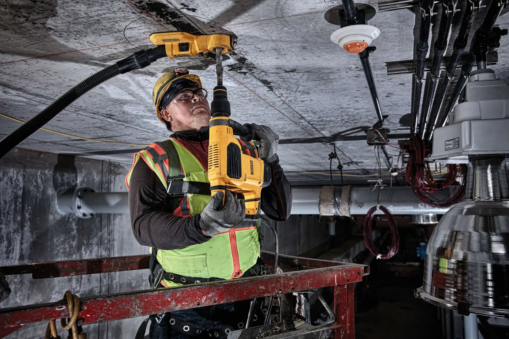 Arbeiter nutzt eine DEWALT-Bohrmaschine am Deckenbau, trägt Schutzkleidung und Warnweste.