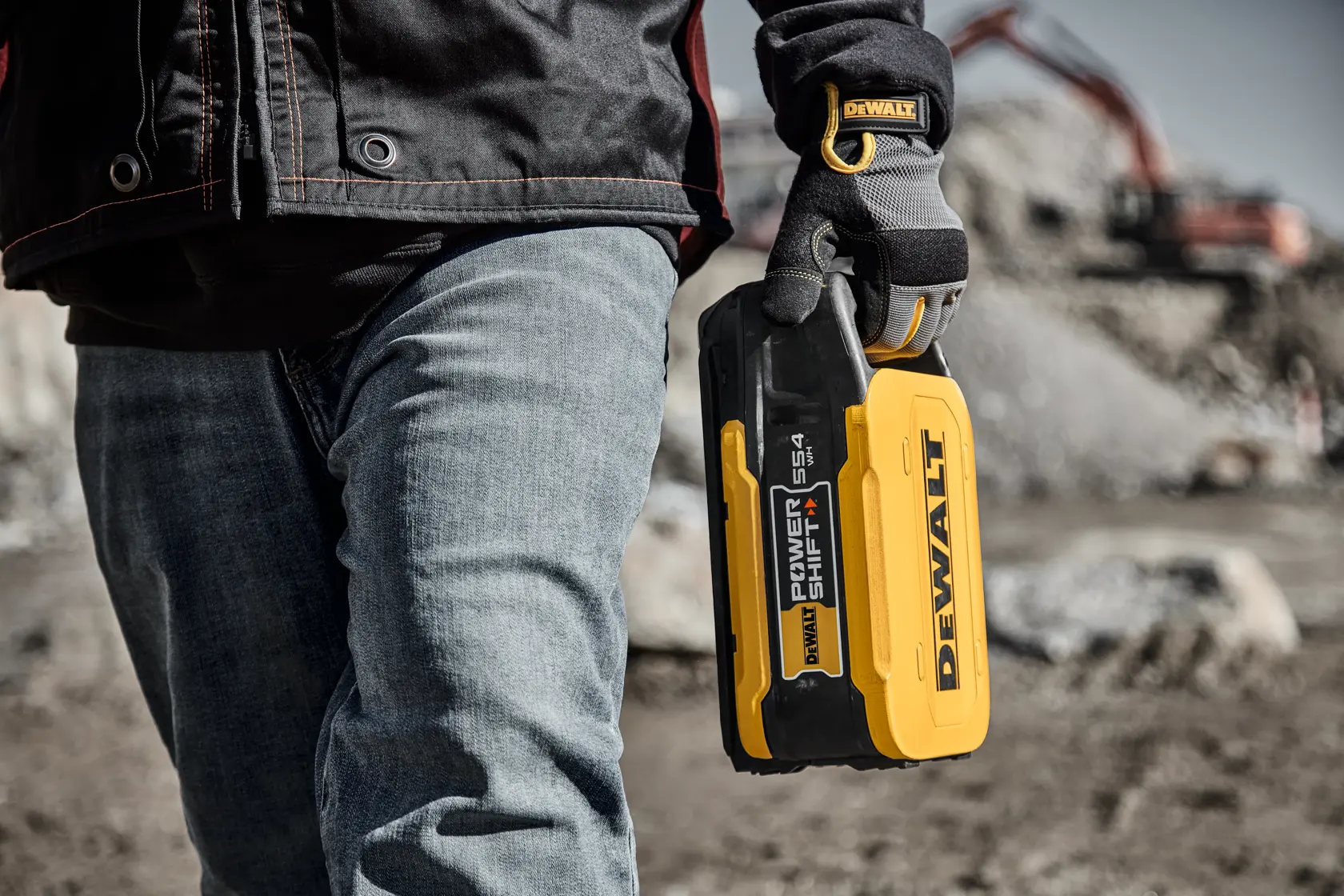 DEWALT Power Shift DCBPS0554 Akku wird von einem Arbeiter mit Handschuhen an Baustelle gehalten.