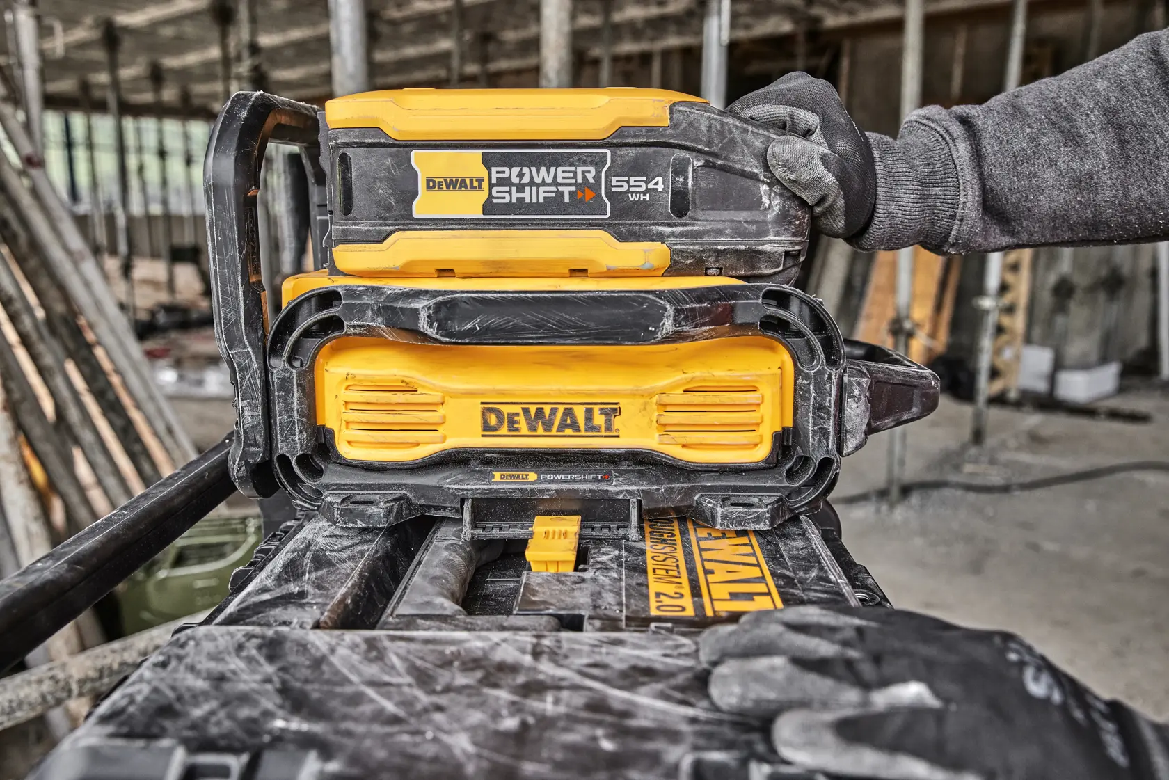 Sistema de batería DEWALT PowerShift en obra, manos enguantadas visibles.