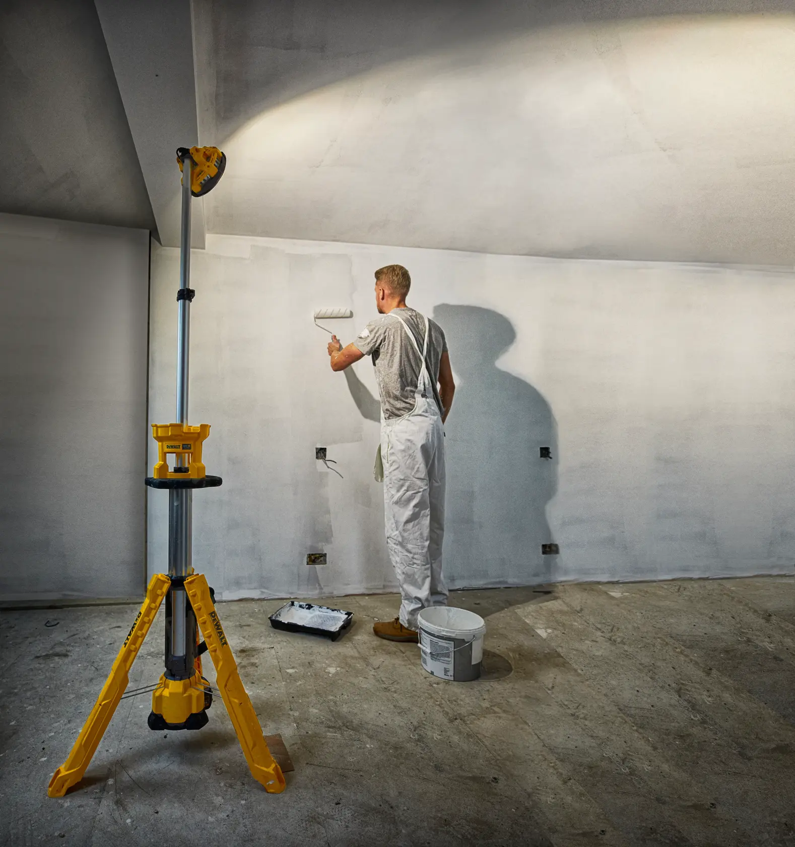 Photo of DEWALT DCL079-XJ, DCL079 tripod work light illuminating a painter working on a wall indoors.