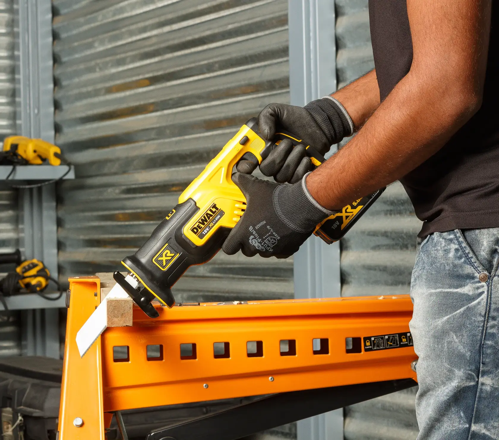 Photo of DEWALT DCS367P2 cordless reciprocating saw cutting wood, held by gloved hand in workshop.