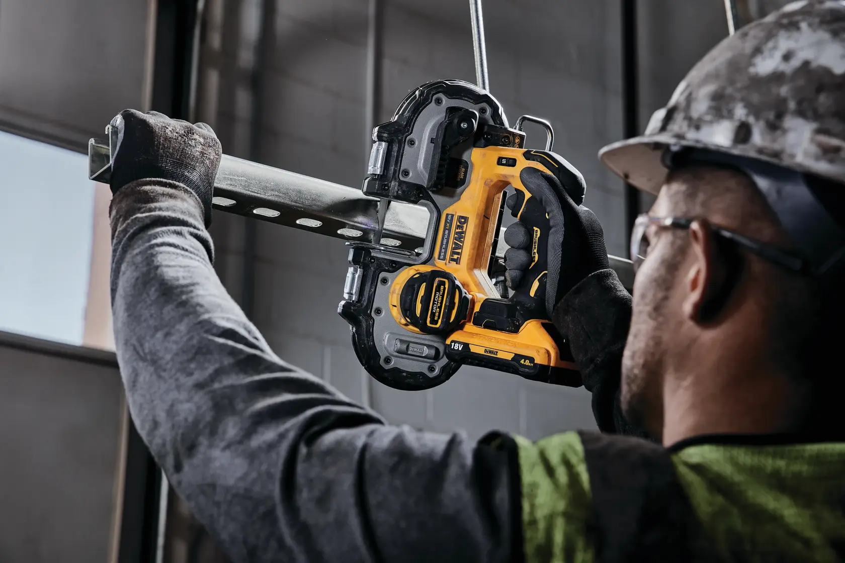 Photo of worker using DEWALT DCS377NT cordless bandsaw to cut a metal pipe indoors.