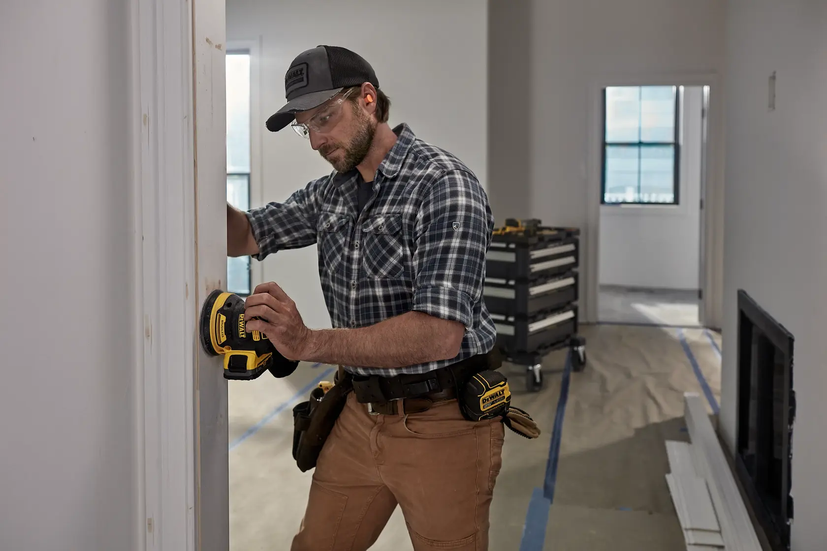 Person uses DEWALT sander DCW210, DCW210D1, DCW210N-XJ on door frame at job site. Photography category.