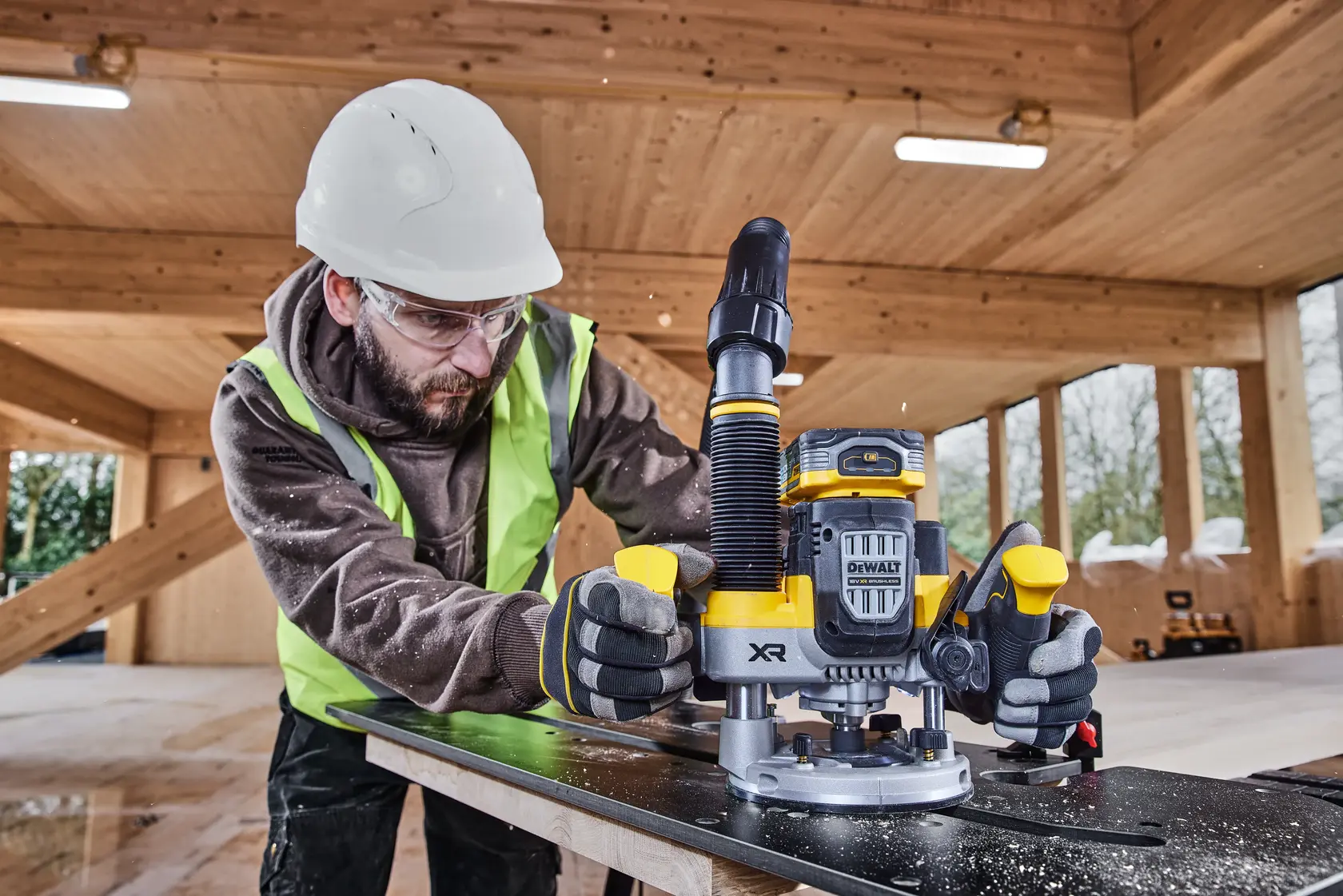 Photo of DEWALT DCW620NT router in use on wood, construction site background, yellow accents, photography.