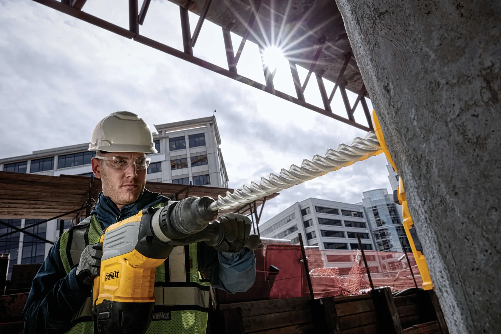 Taladro DEWALT DT60846 en uso en obra, manejado por trabajador con equipo de seguridad cerca de cemento y acero.
