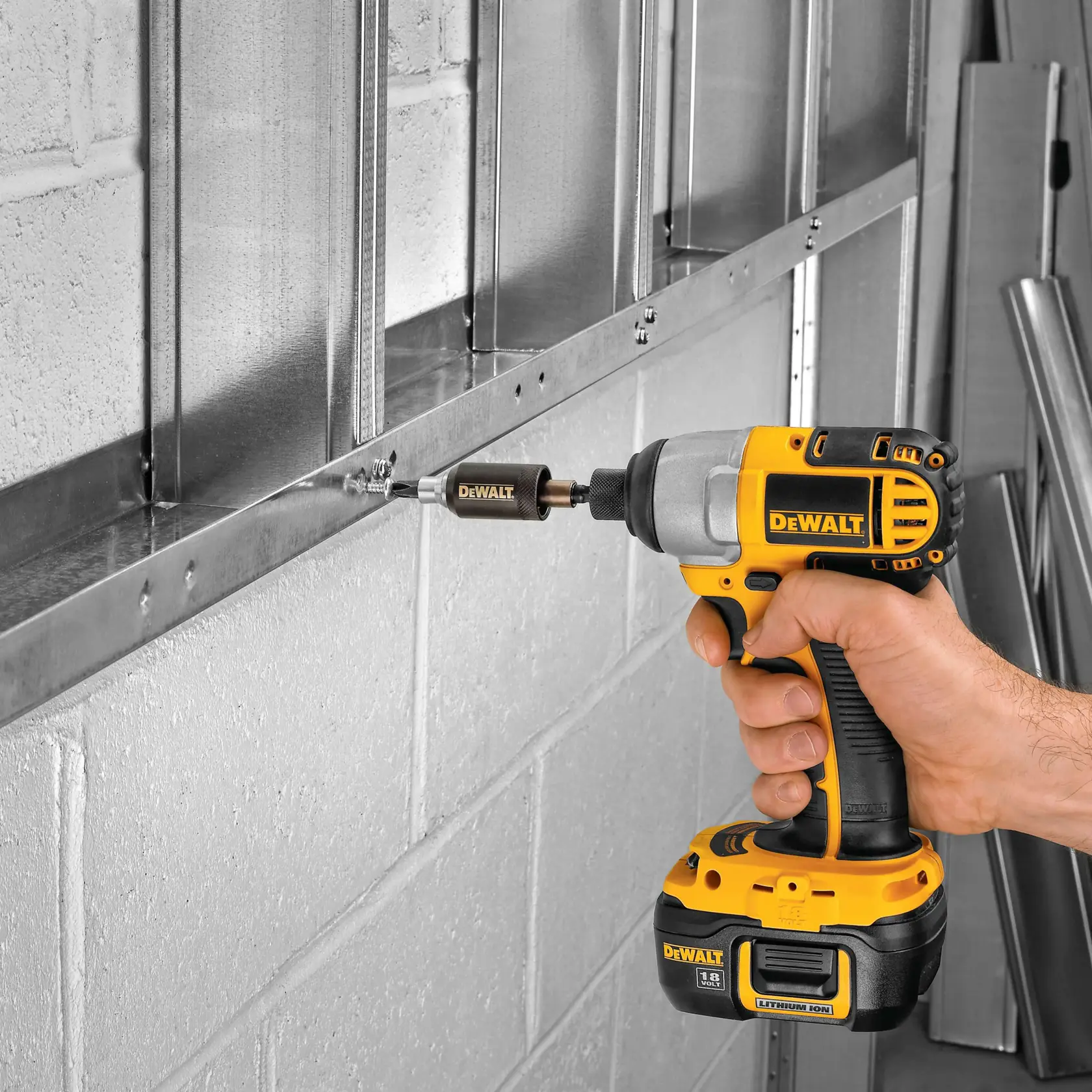 DEWALT cordless drill used to fasten screws into a metal frame against a brick wall.