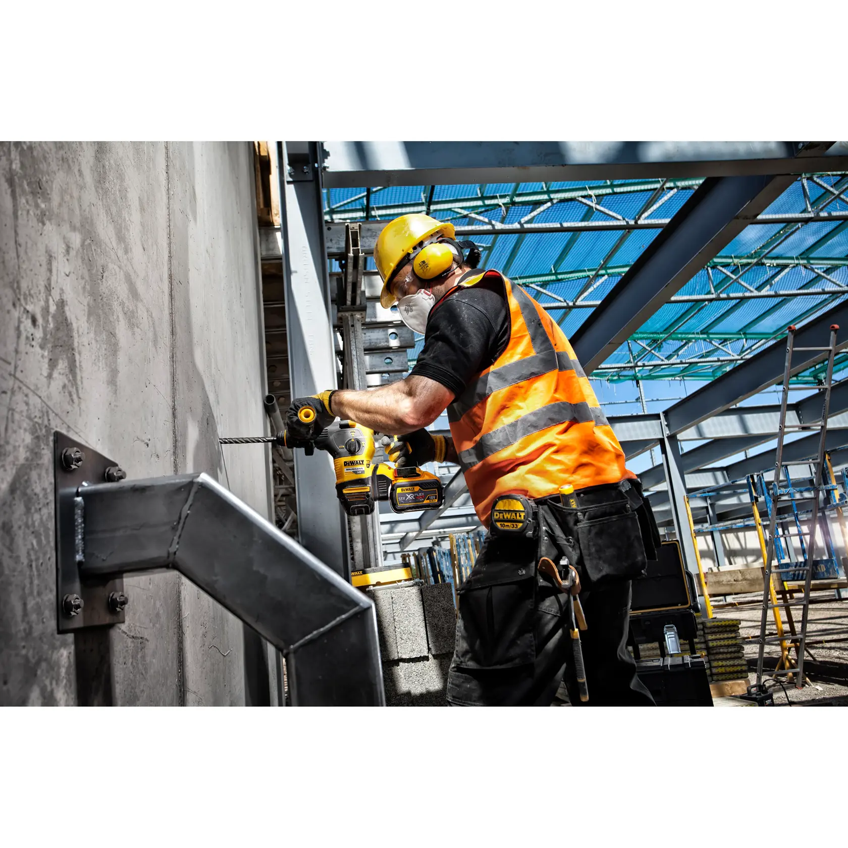 Trabajador perfora muro de concreto con herramienta DEWALT en obra, lleva equipo de seguridad y chaleco naranja.