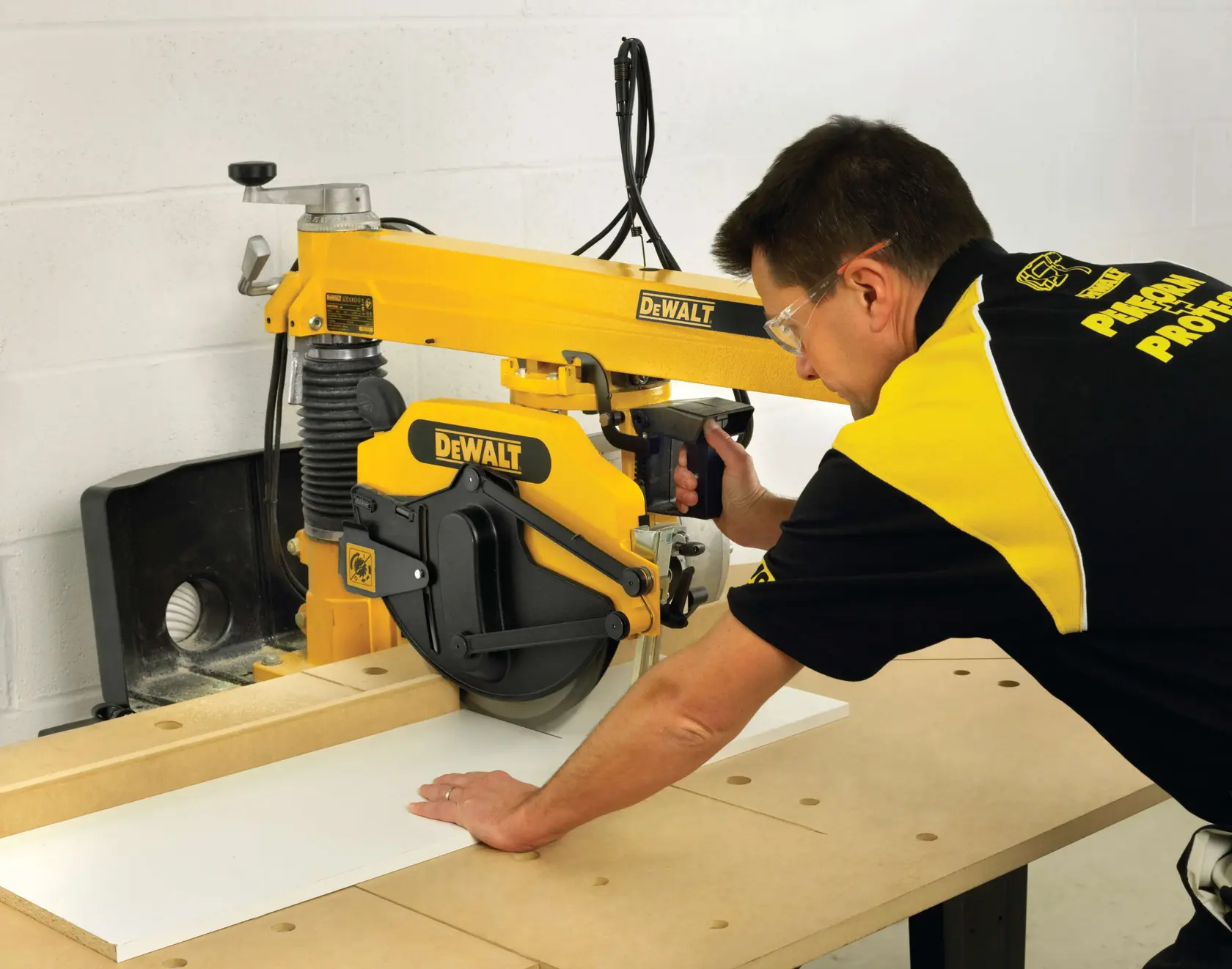 Person cutting wood with a DEWALT DW729KN radial arm saw in a workshop.