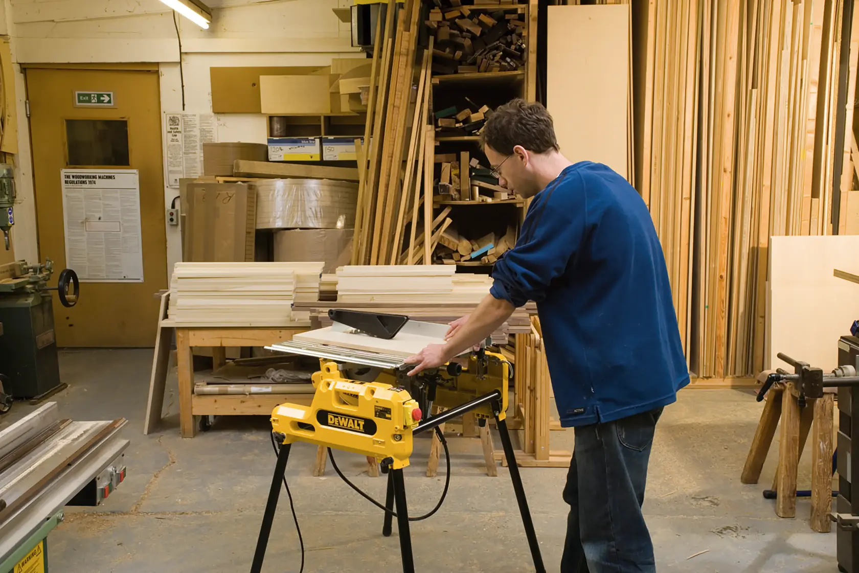 Person using DEWALT DW743N saw in a workshop with wooden boards and tools around.