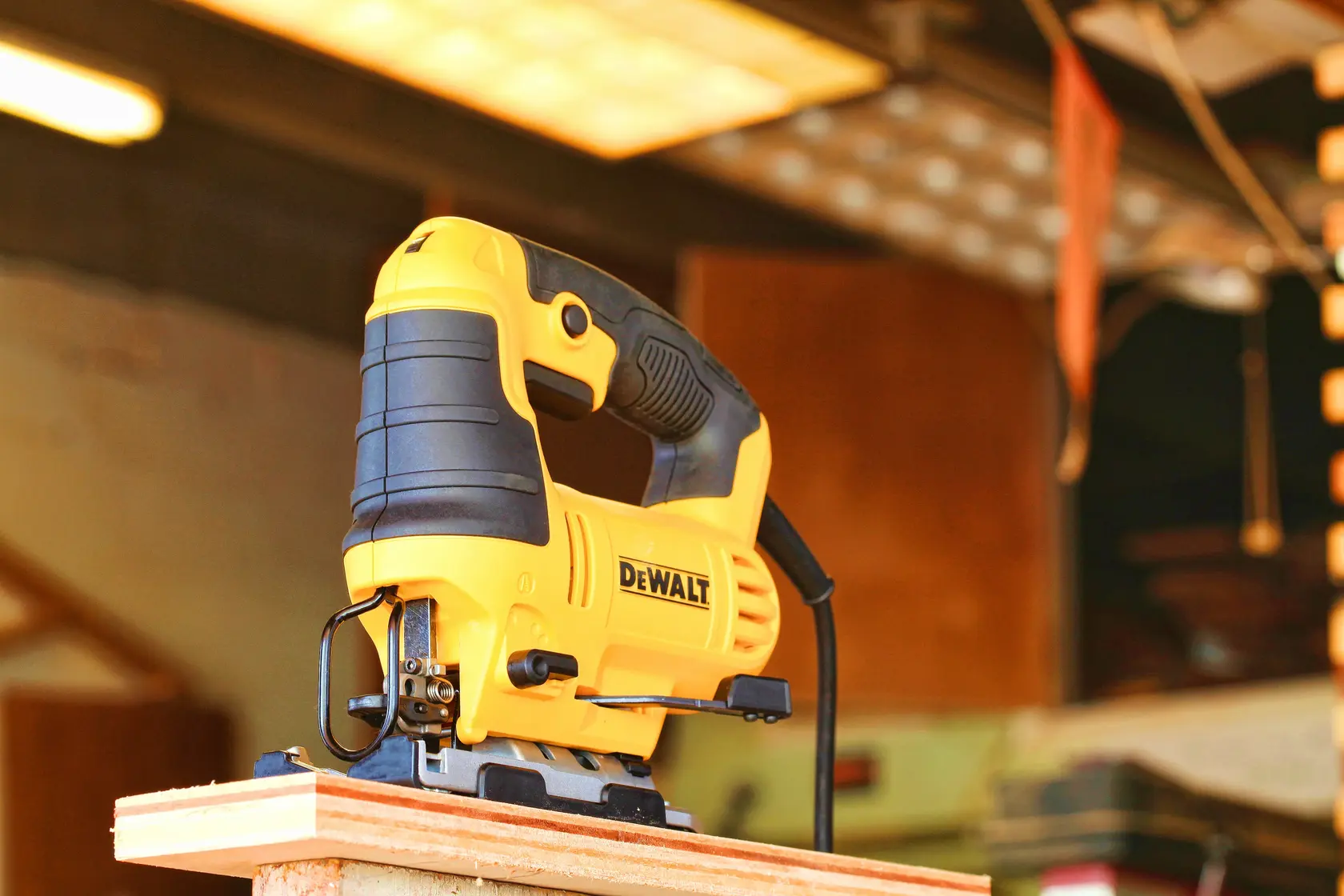 Photo of DEWALT DWE349 jigsaw in yellow and black on wood plank, workshop background, power tool category.