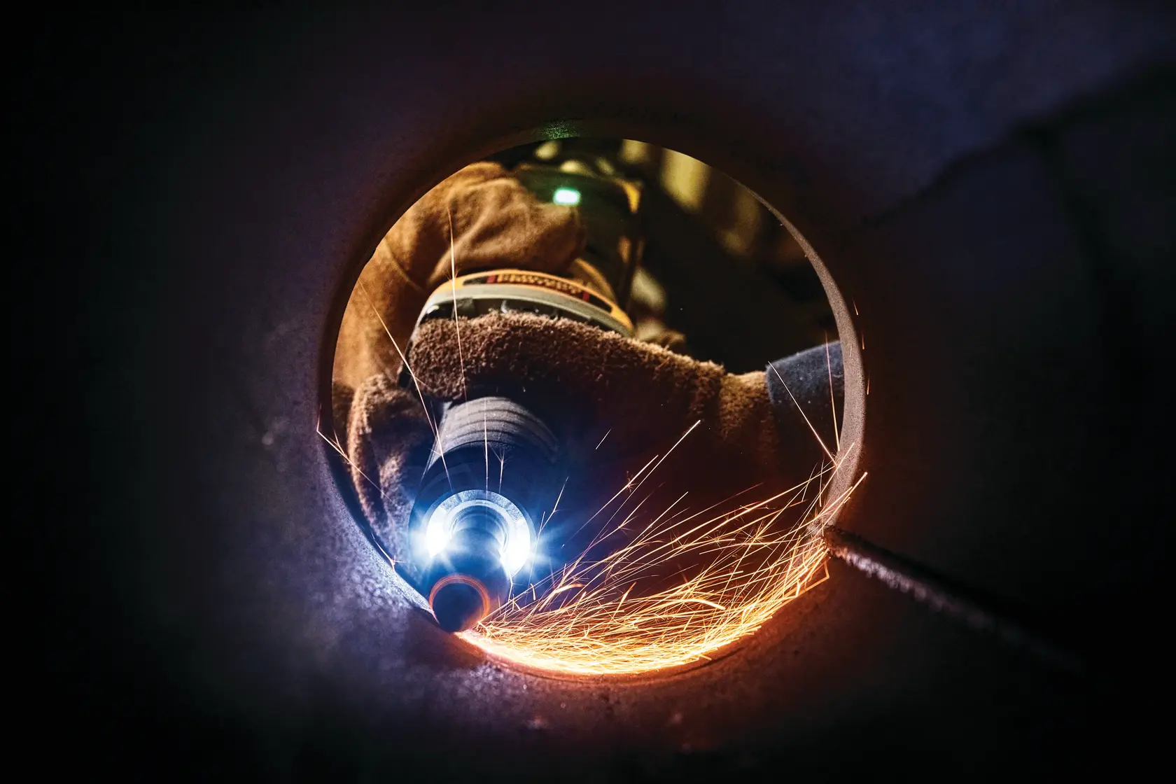 Photo of DEWALT DWE4997 grinder in action creating sparks inside pipe, close-up view.