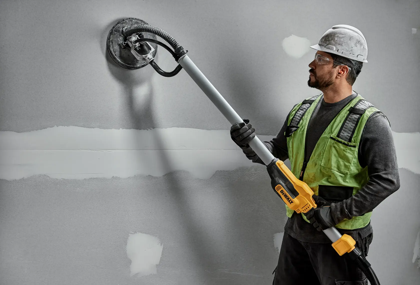 Worker uses DEWALT DWE7800, DWE7800-QS wall sander on drywall. Photography product shown in action.